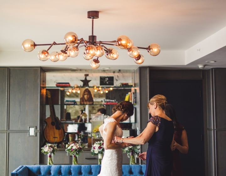 A luxurious lobby with a chandelier, blue couch, and flowers.