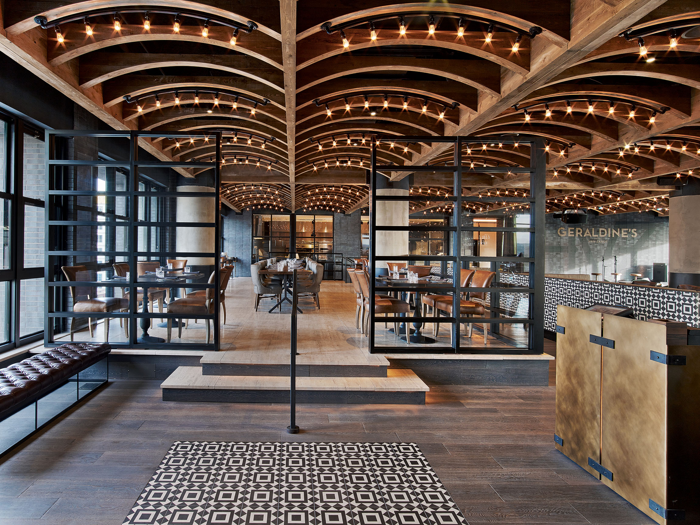 A modern dining area with arched ceiling, glass walls, and table settings.