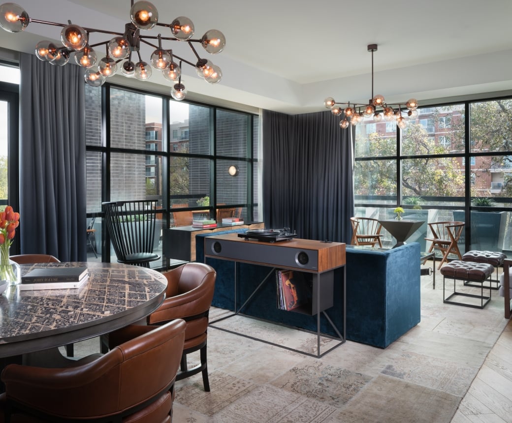 A wide view of a luxurious suite with a dining area, desk, sofa, and chairs.