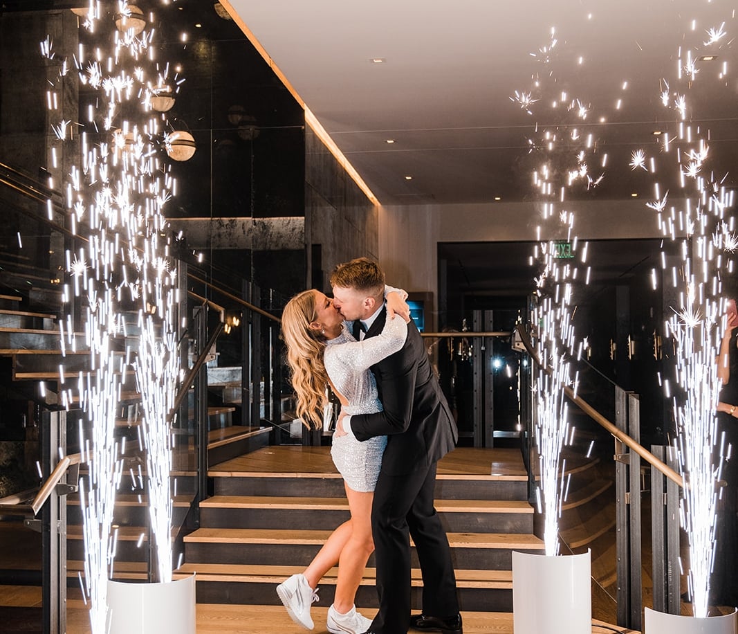 a couple kissing on a staircase with sparkler-like lighting