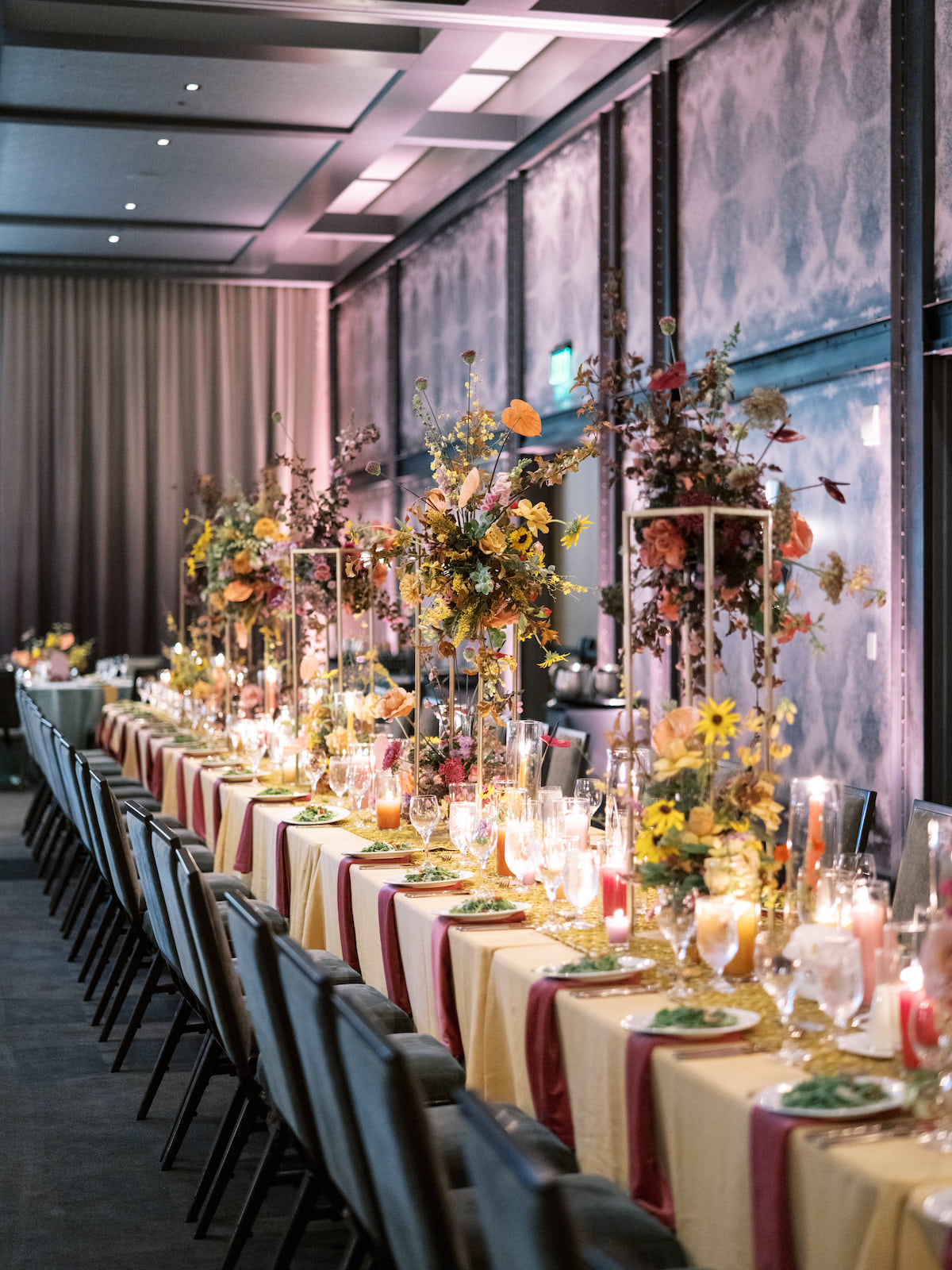 A long table set for a formal dinner with flowers, candles, and fine china.