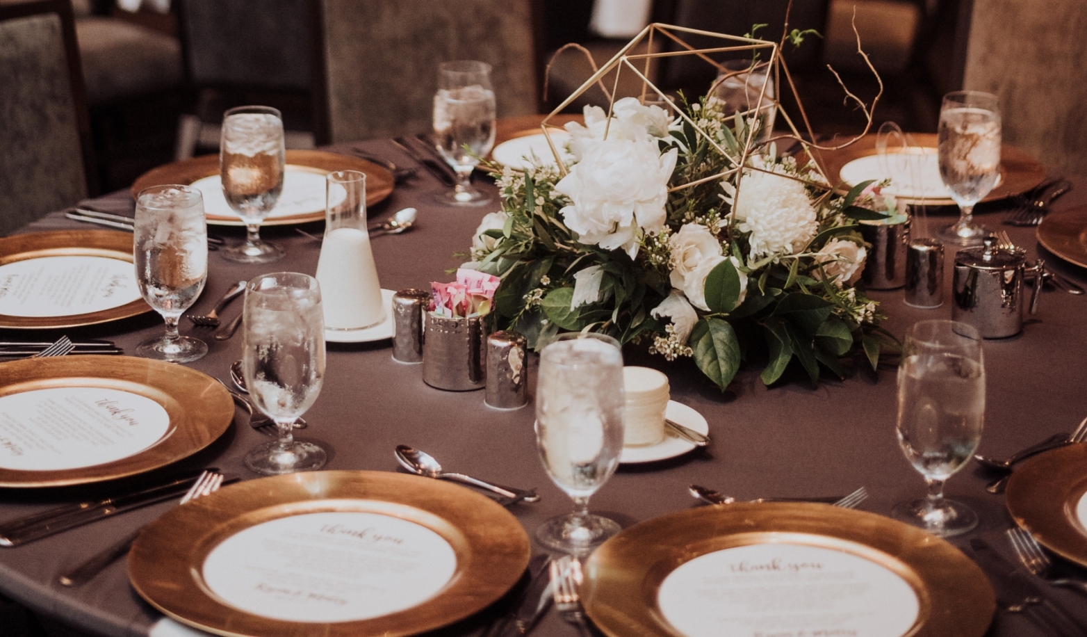 A formal dining table set with flowers and gold plates