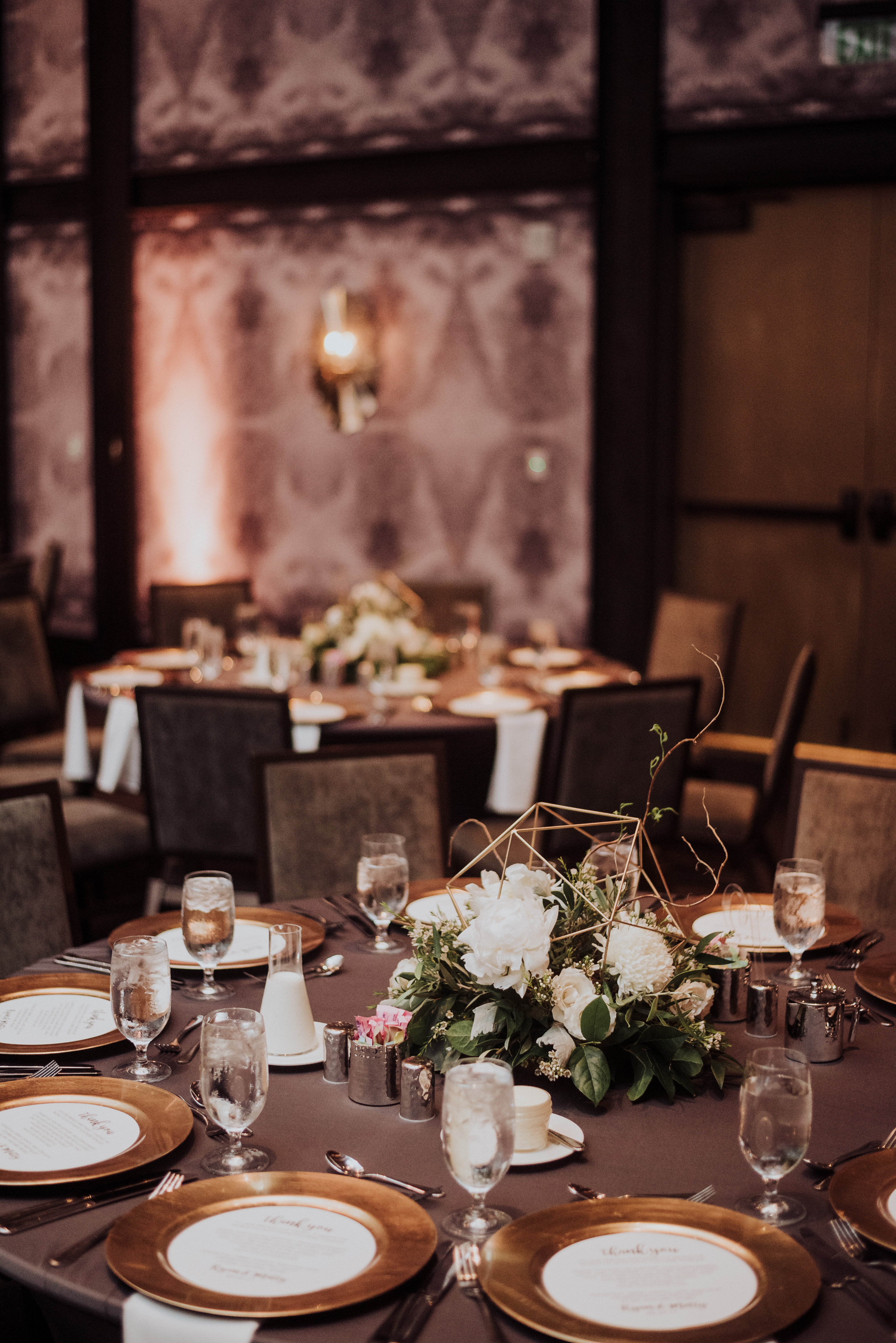 A dining room with tables set for a meal, adorned with flowers and glasses.