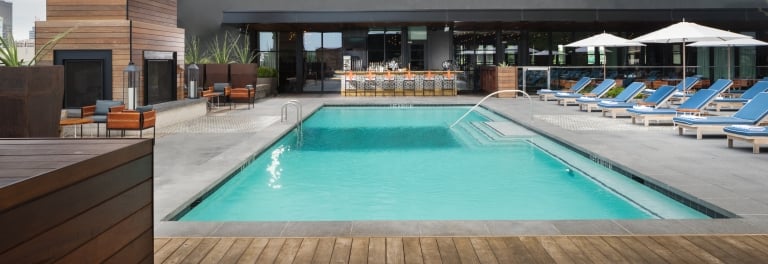 A rectangular pool with lounge chairs and a bar in the background.