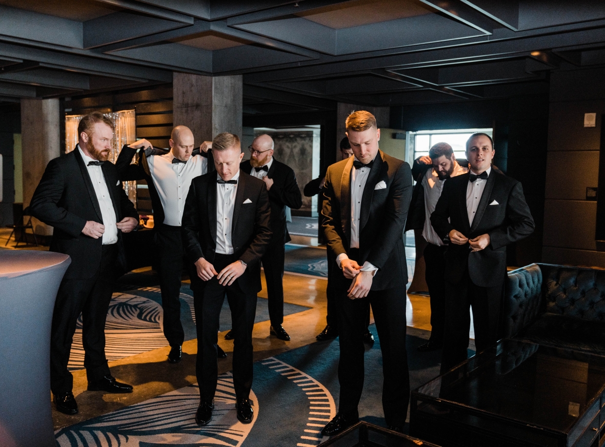 A group of men in tuxedos standing in a hotel lobby