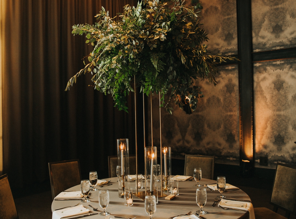 A round dining table set with a floral centerpiece, candles, and fine china.
