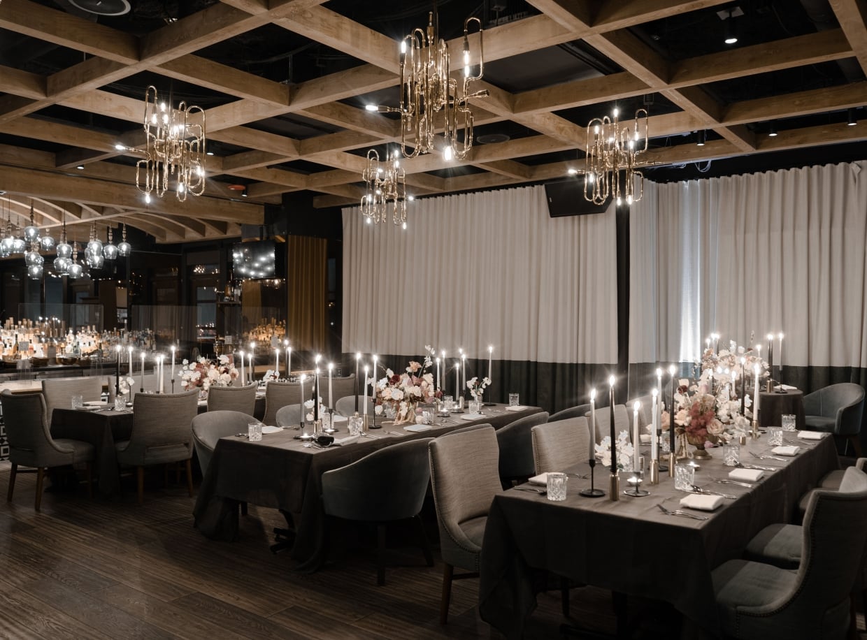 A formal dining room with tables set for a meal, decorated with flowers and candles.