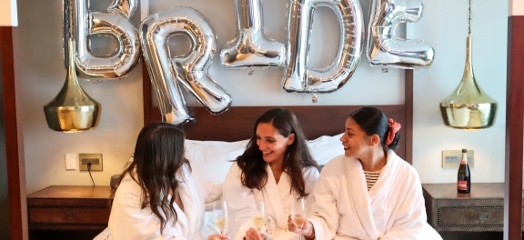 three women sitting on the bed with drinks