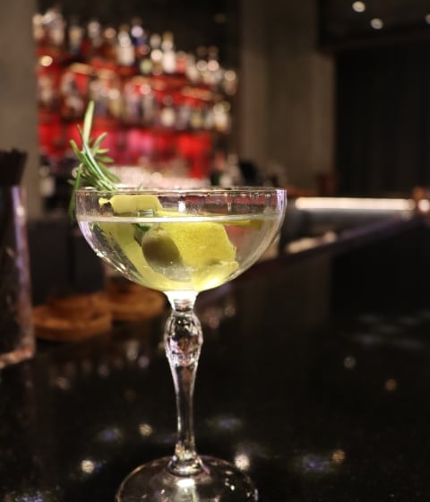 a cocktail with ice and rosemary in a bar