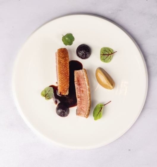 An overhead shot of a dish with seared tuna slices arranged in a vibrant green sauce