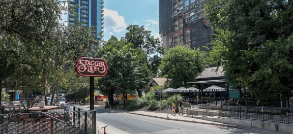 Tree-lined Rainey Street in Austin with the Stagger Lee neon sign