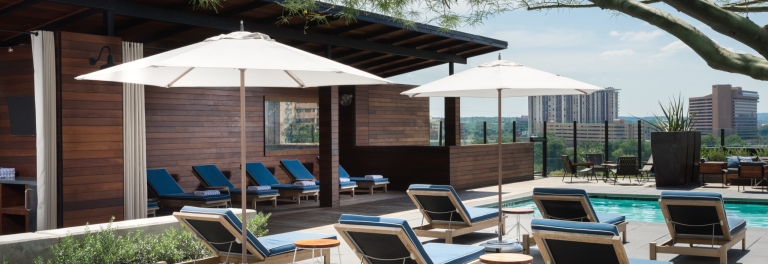 Rooftop pool deck with navy lounge chairs, umbrellas and cabanas at Hotel Van Zandt