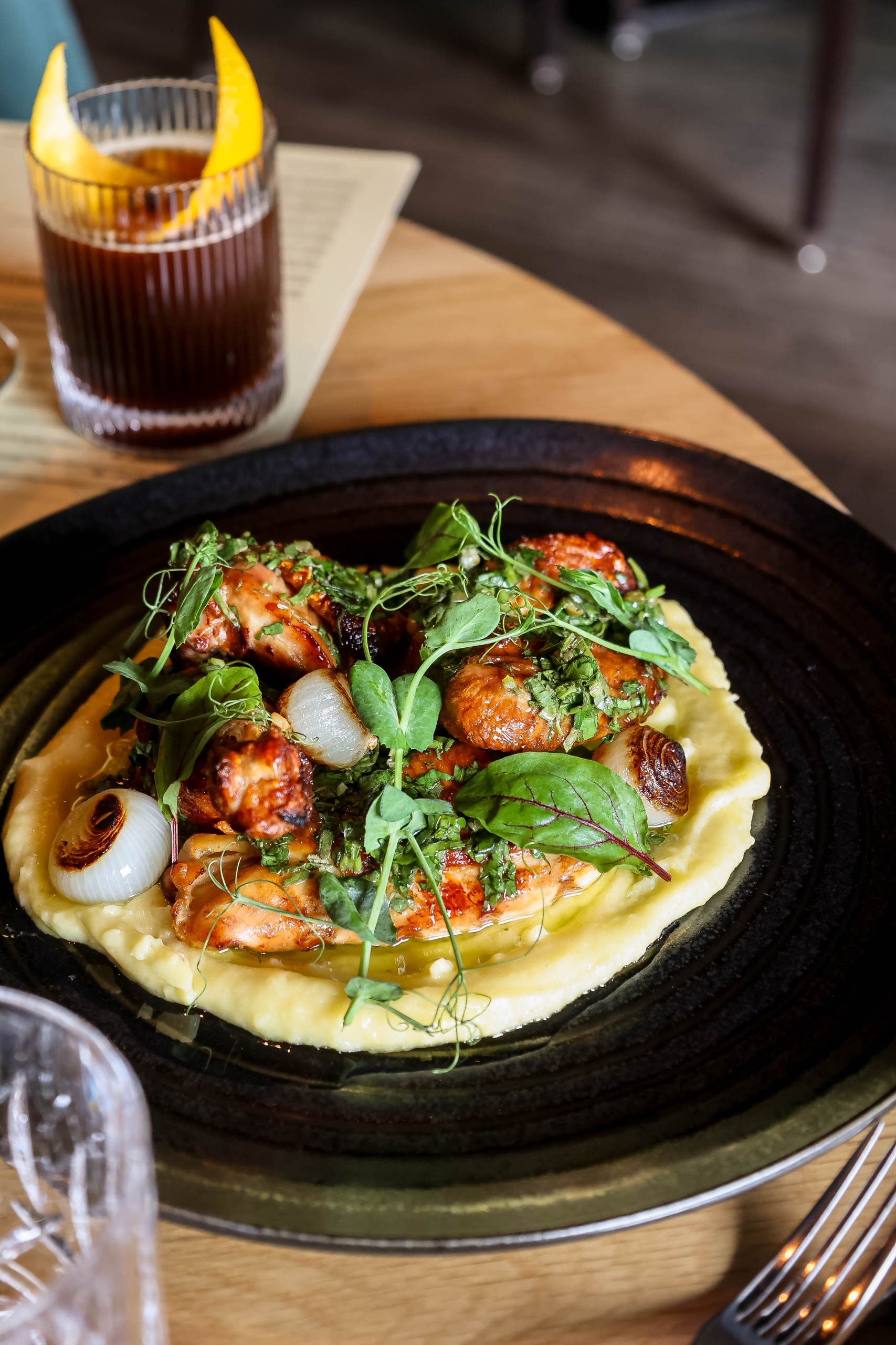Glazed grilled prawns over silky purée, topped with microgreens and charred spring onion, at Geraldine's
