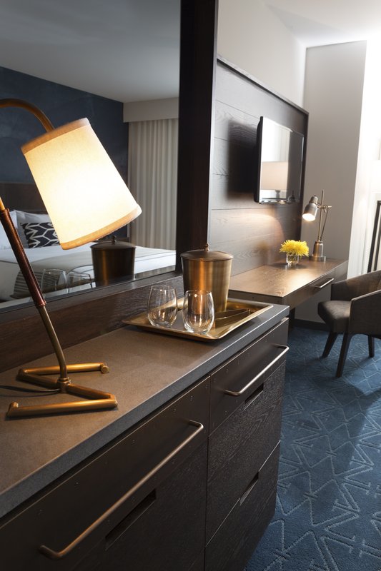 Hotel suite dresser with brass accents, dark wood cabinetry, and writing desk