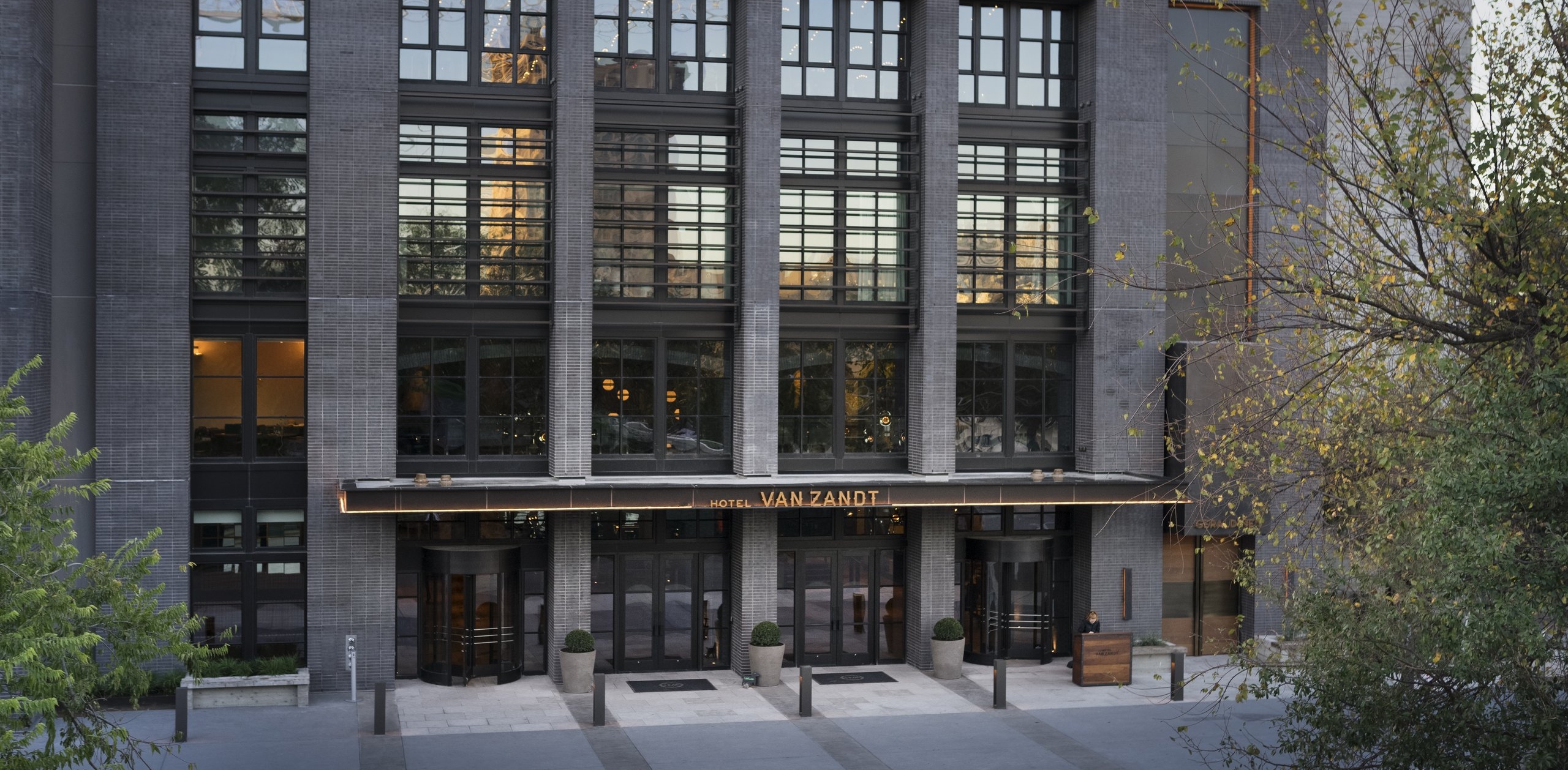 A gray brick building with a glass awning and gold lettering reading 'HOTEL VAN ZANDT'